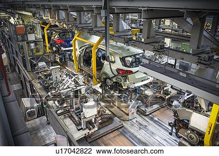 Stock Image - Car bodies being married with engines and suspension in car factory. Fotosearch