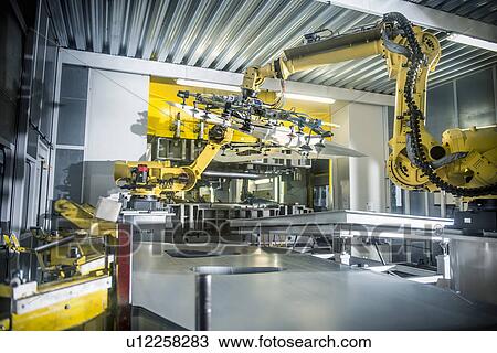 Stock Image - Car parts handled by robots in car factory. Fotosearch