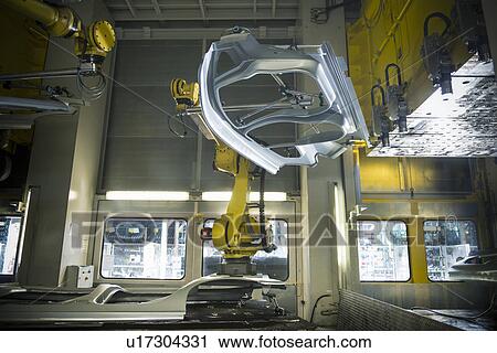 Stock Image - Car parts handled by robots in car factory. Fotosearch