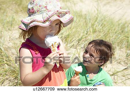 Stock Photo - Children eating ice cream on beach. Fotosearch