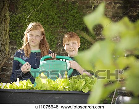 Children holding watering can in garden View Large Photo Image Stock Photograph - Children holding watering can in garden. Fotosearch