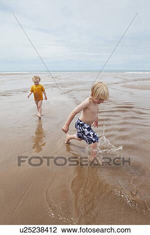 Children playing in waves on beach View Large Photo Image Stock Image - Children playing in waves on beach. Fotosearch