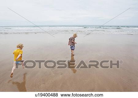 Children playing in waves on beach View Large Photo Image Stock Photo - Children playing in waves on beach. Fotosearch