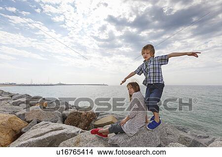Picture - Children playing on rocks at beach. Fotosearch