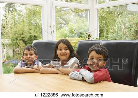 Stock Photograph - Children smiling at table. Fotosearch