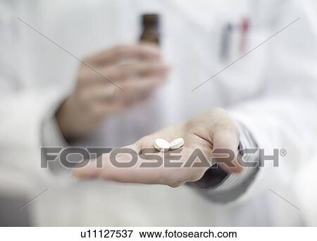 Stock Photo - Close up of doctor holding pills. Fotosearch