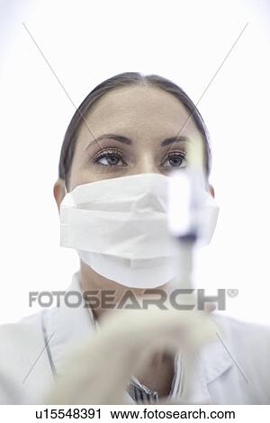 Stock Image - Close up of doctor preparing syringe. Fotosearch