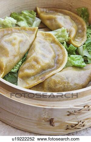 Stock Image - Close up of dumplings in steamer. Fotosearch