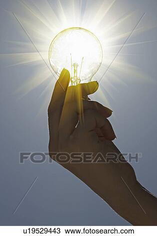 Stock Image - Close up of hand holding light bulb. Fotosearch