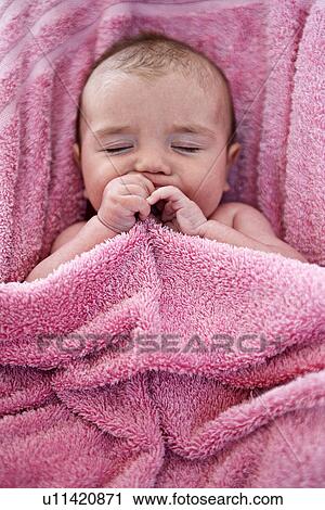 Stock Image - Close up of infant in pink towel. Fotosearch
