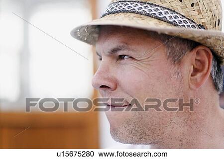 Stock Image - Close up of man wearing straw hat. Fotosearch