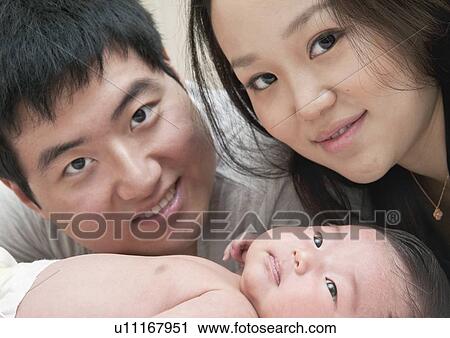 Stock Image - Close up of parents smiling with baby. Fotosearch