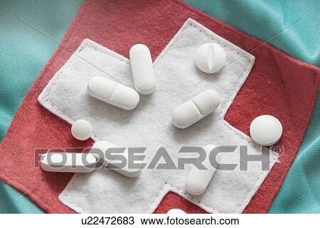 Stock Image - Close up of pills on red cross patch. Fotosearch
