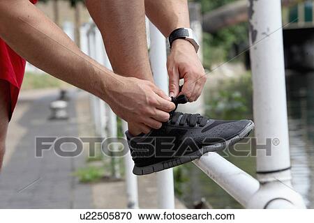 Stock Image - Close up of runner tying laces. Fotosearch