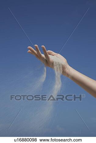 Stock Photo - Close up of sand pouring from hand. Fotosearch