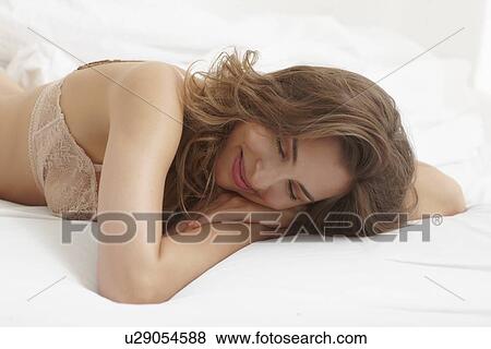 Stock Photo - Close up of smiling woman asleep on bed. Fotosearch