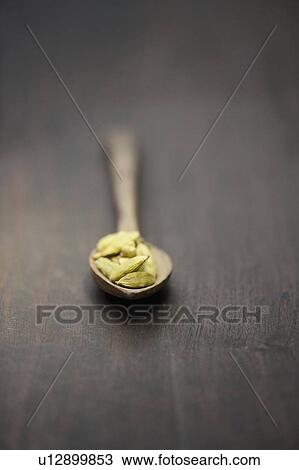 Stock Image - Close up of spoon of cardamom pods. Fotosearch