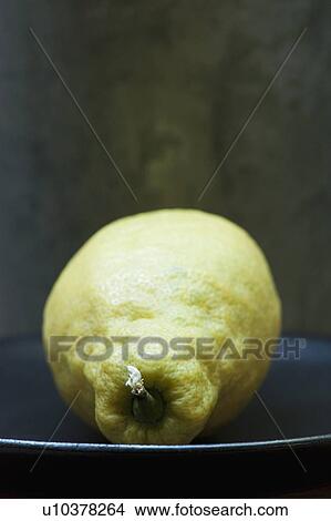 Picture - Close up of unwaxed lemon on plate. Fotosearch
