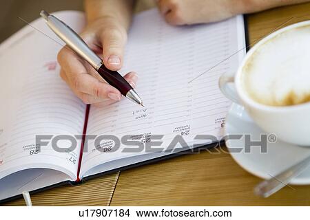 Close up of woman writing in planner View Large Photo Image Picture - Close up of woman writing in planner. Fotosearch