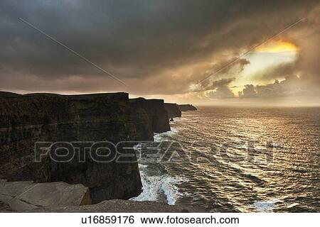 Stock Photograph - Colorful clouds over coastal cliffs. Fotosearch