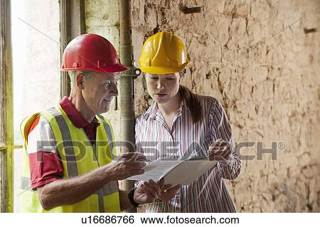 Stock Photograph - Construction workers examining papers. Fotosearch