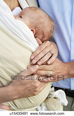 Stock Image - Couple holding infant outdoors. Fotosearch