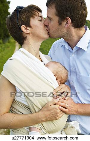 Couple kissing with infant outdoors View Large Photo Image Picture - Couple kissing with infant outdoors. Fotosearch