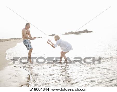 Couple playing in waves on beach View Large Photo Image Picture - Couple playing in waves on beach. Fotosearch