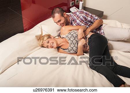 Couple relaxing on hotel room bed View Large Photo Image Stock Image - Couple relaxing on hotel room bed. Fotosearch
