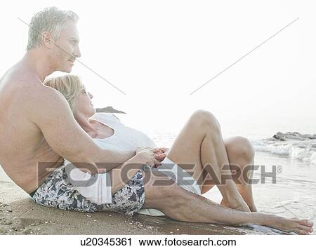 Couple relaxing together on beach View Large Photo Image Stock Image - Couple relaxing together on beach. Fotosearch