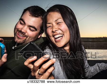 Couple using cell phones outdoors View Large Photo Image Stock Photo - Couple using cell phones outdoors. Fotosearch