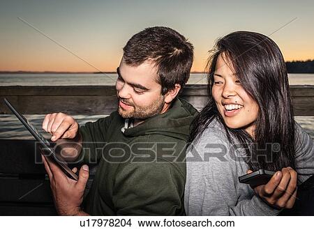 Couple using tablet computer outdoors View Large Photo Image Picture - Couple using tablet computer outdoors. Fotosearch