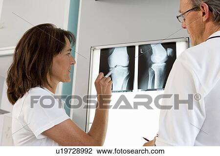 Stock Image - Doctor and nurse examining x-rays. Fotosearch