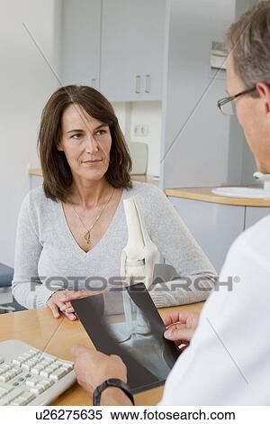 Stock Photography - Doctor examining x-rays with patient. Fotosearch