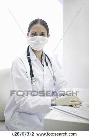 Doctor wearing facemask in office View Large Photo Image Stock Image - Doctor wearing facemask in office. Fotosearch