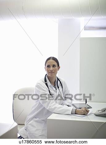 Stock Photography - Doctor writing notes at desk. Fotosearch
