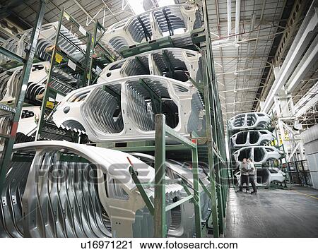 Stock Image - Engineers with pressed car parts in car factory. Fotosearch
