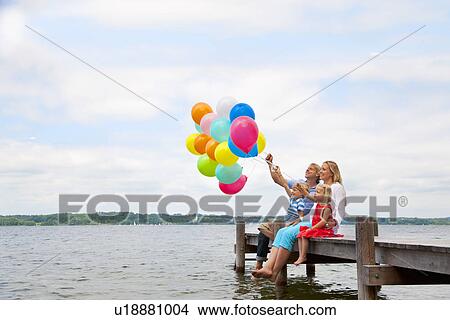 Family holding balloons on wooden pier View Large Photo Image Picture - Family holding balloons on wooden pier. Fotosearch