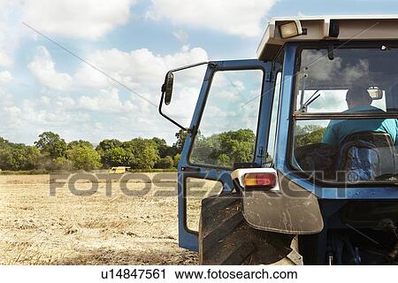 Farmer sitting in tractor in crop field View Large Photo Image Stock Image - Farmer sitting in tractor in crop field. Fotosearch