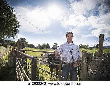 Farmer standing by gate with cow View Large Photo Image Stock Photo - Farmer standing by gate with cow. Fotosearch