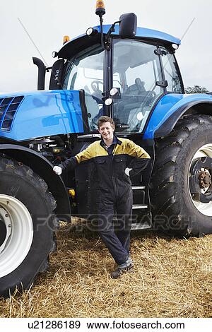 Stock Photo - Farmer standing by tractor in field. Fotosearch