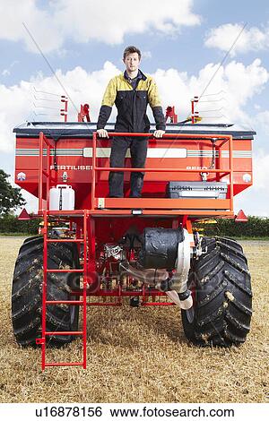 Farmer standing on tractor in field View Large Photo Image Stock Photograph - Farmer standing on tractor in field. Fotosearch