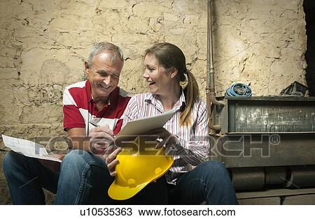 Stock Image - Father and daughter examining papers. Fotosearch