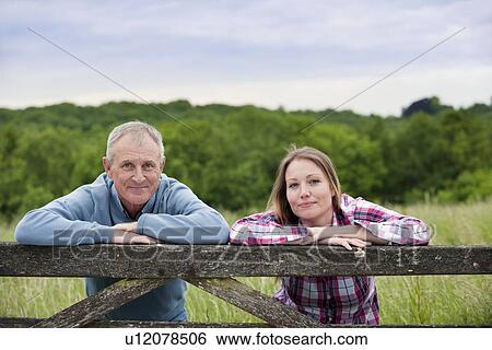 Stock Photograph - Father and daughter on wooden fence. Fotosearch