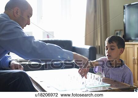 Stock Image - Father and son playing chess together. Fotosearch