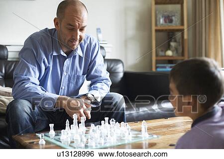 Stock Photograph - Father and son playing chess together. Fotosearch