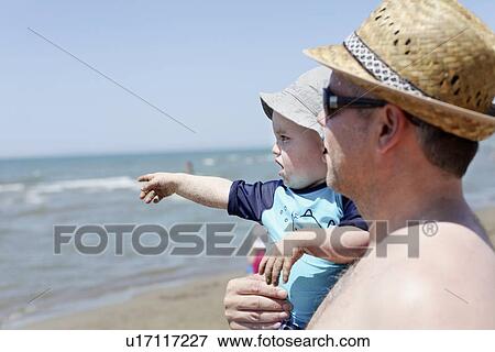 Father holding toddler on beach View Large Photo Image Stock Photo - Father holding toddler on beach. Fotosearch