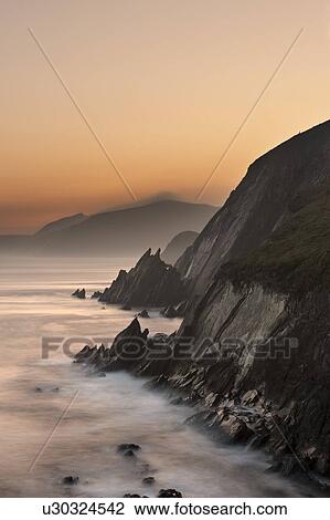 Stock Image - Fog rolling up to coastal cliffs. Fotosearch