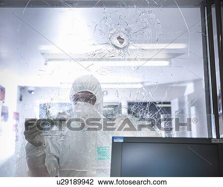 Stock Image - Forensic scientist at shattered window. Fotosearch
