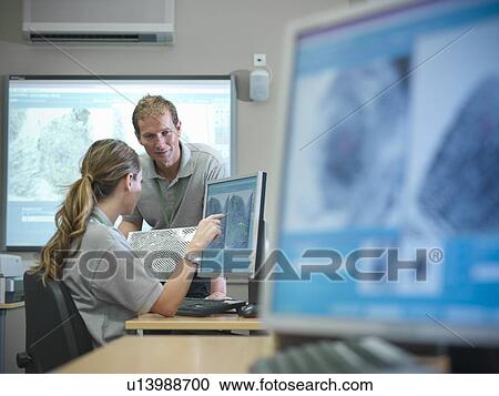 Stock Image - Forensic students examining fingerprints. Fotosearch